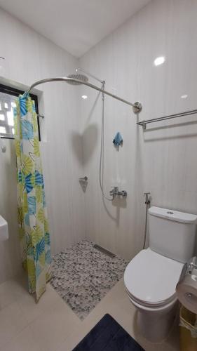 a bathroom with a toilet and a shower with a shower curtain at Casa Munti Garden Lodge in Daet