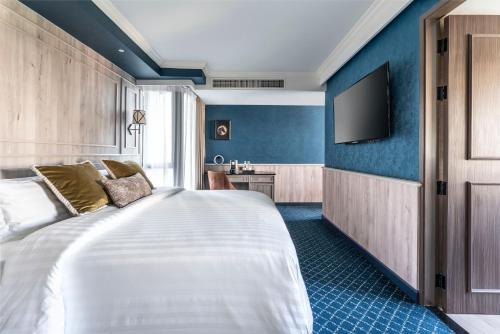 a hotel room with a bed and a television at The Coach Hotel Sukhumvit - Asok BTS Bangkok in Bangkok
