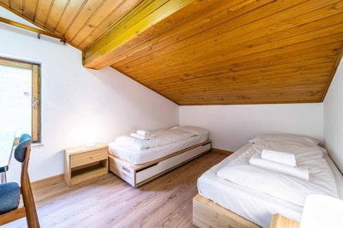 two beds in a room with a wooden ceiling at Casa Mirabella in Sottoguda