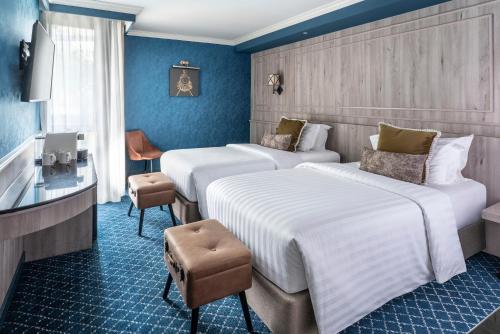 a hotel room with three beds and a television at The Coach Hotel Sukhumvit - Asok BTS Bangkok in Bangkok