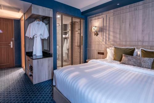a bedroom with a large white bed and a dresser at The Coach Hotel Sukhumvit - Asok BTS Bangkok in Bangkok