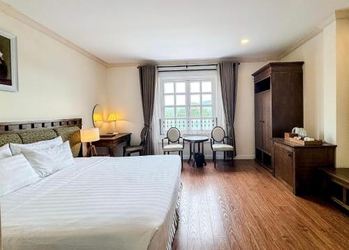 a bedroom with a bed and a desk and a window at Phoenix Hotel Vung Tau in Vung Tau