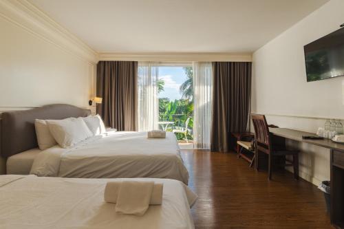 a hotel room with two beds and a desk at บ้านสวนสมบูรณ์ in Sangkhla Buri
