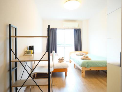 a bedroom with a bed and a desk and a bed and a window at Osaka English House in Hirakata