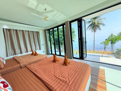 two beds in a bedroom with a view of the ocean at Koh Chang Pool Villa Viewthalay in Ko Chang