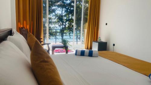 a bedroom with a large bed and a large window at Sunray Beach House in Tangalle
