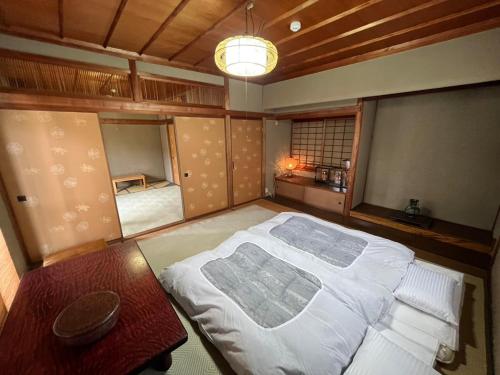a bedroom with a large white bed and a table at 丸亀 Sawai 一棟貸し 丸亀駅徒歩 10人まで宿泊可能 駐車場2台有 子供部屋ベビーベッド有 in Marugame