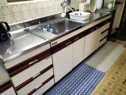 a kitchen with a stainless steel sink and a blue rug at 丸亀 Sawai 一棟貸し 丸亀駅徒歩 10人まで宿泊可能 駐車場2台有 子供部屋ベビーベッド有 in Marugame