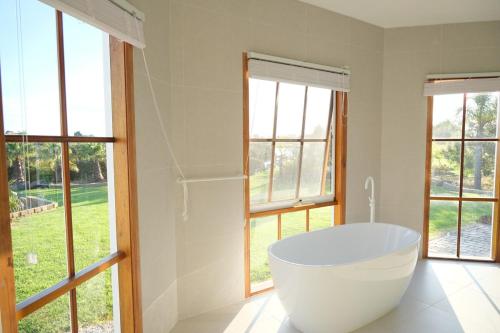 a white bath tub in a bathroom with windows at Bloom by the Bend in Tooradin