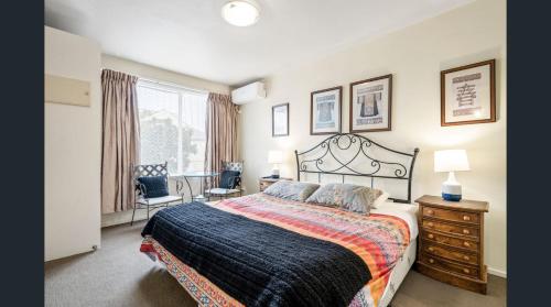 a bedroom with a bed and a chair and a window at Knightsbridge Apartments in Melbourne