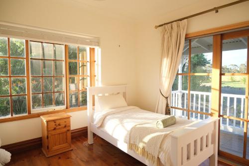 a bedroom with a white bed and windows at Bloom by the Bend in Tooradin