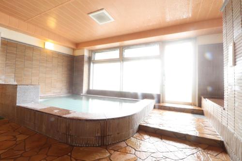 a hot tub in a room with a large window at ホテルクオーレ敦賀 男性専用の大浴場サウナをご用意 in Tsuruga