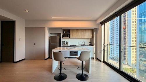 a kitchen with a table and chairs in a room with large windows at Departamento Elysian High Country in Guadalajara