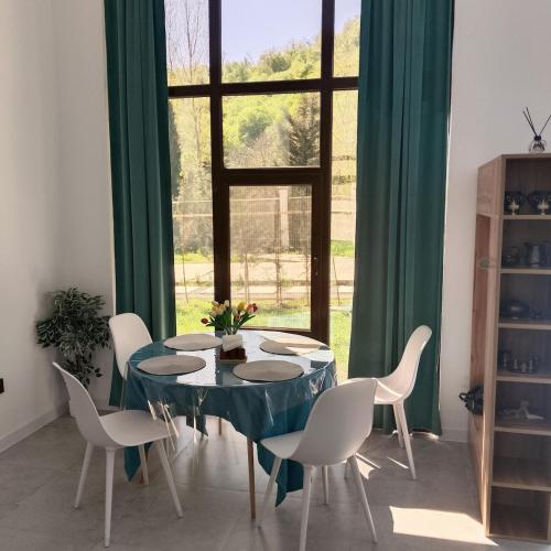 ein Esszimmer mit Tisch und Stühlen und einem Fenster in der Unterkunft Harmony Hideaway Gabala in Qəbələ