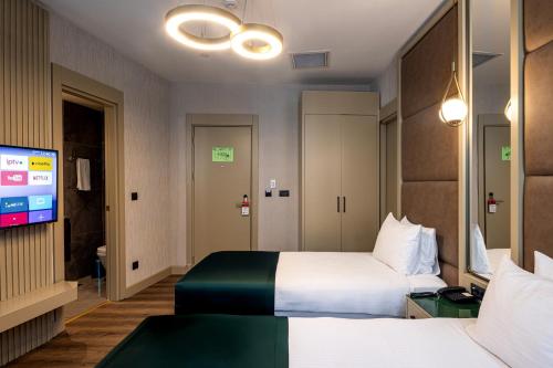 una camera d'albergo con due letti e una TV a schermo piatto di THE NEST HOTEL a Istanbul