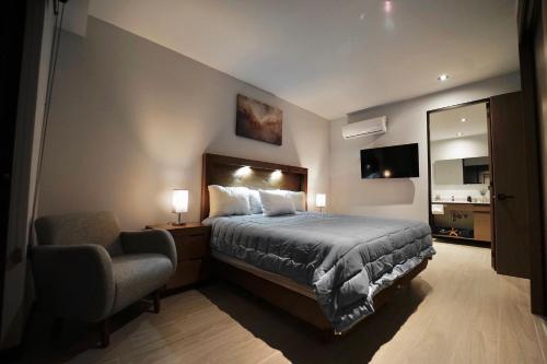a bedroom with a bed and a chair and a mirror at Departamento Elysian High Country in Guadalajara