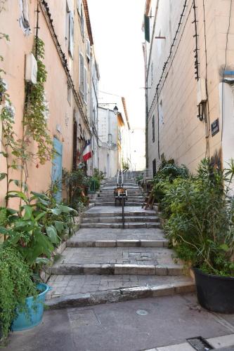 an empty alley with plants in an alley between two buildings at Sous le Clocher in Marseille