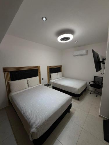 a hotel room with two beds and a desk at Acapulco Diamante Departamento Olimpya in Acapulco