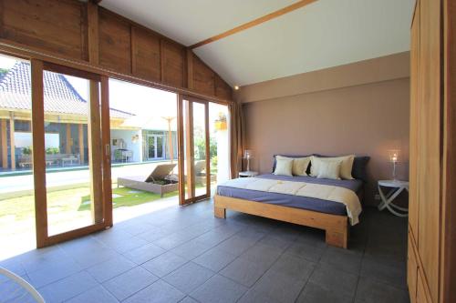 a bedroom with a bed and some sliding glass doors at Villa Mitsouko by Optimum Bali Villas in Seminyak