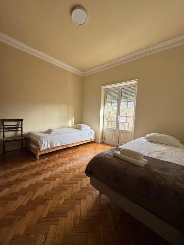 a bedroom with two beds and a window and wooden floors at Varanda dos Poetas in Lisbon