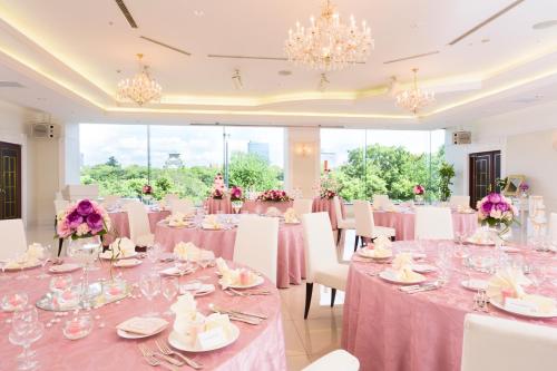 a banquet hall with pink tables and chairs and chandeliers at KKR Hotel Osaka in Osaka