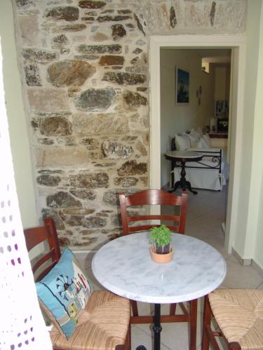 a table and chairs in a room with a stone wall at Antouanetta Apartments in Ermoupoli