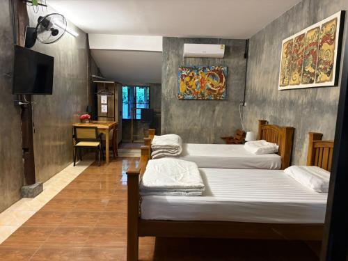 a room with four beds and a tv and a desk at The Bodhi House in Chiang Mai