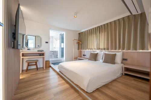 a bedroom with a white bed and a desk at SMilE WAVE in Xiaoliuqiu