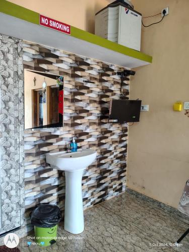 a bathroom with a sink and a tv on a wall at D'Souza Home stay in Māvalli