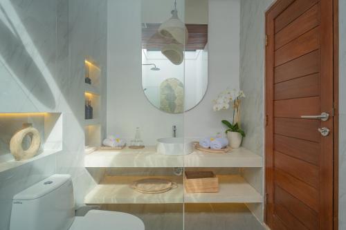 a bathroom with a toilet and a sink and a mirror at Monstera Uluwatu in Uluwatu