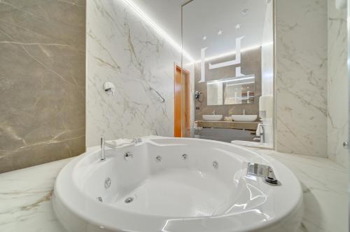 a white bath tub in a bathroom with a mirror at Liberty Hotel in Turin