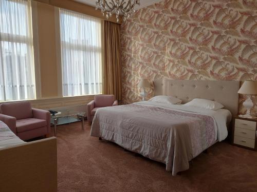 ein Schlafzimmer mit einem großen Bett und zwei Stühlen in der Unterkunft Hotel Excelsior in Den Haag