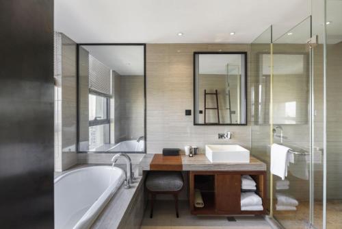 a bathroom with a bath tub and a sink and a bath tub at SSAW Boutique Hotel Dexin Mogan Mountain in Deqing