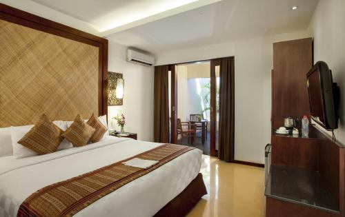 a bedroom with a large bed and a television at Best Western Kuta Villa in Kuta