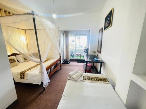 a room with two beds and a desk in it at Namaya Nature Resort & Cafe in Kandy