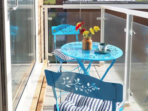 a blue table and chairs on a balcony with a cup and flowers at Galley Hill Aspect in Bexhill