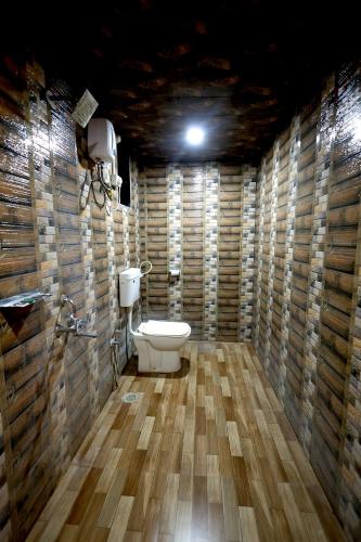a bathroom with a toilet in a wooden wall at Suryavan Holidays in Chinchavli