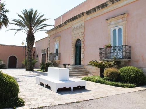 a white bench in front of a pink building at Villa Principe Di Belmonte in Ispica