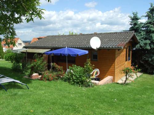 a house with a blue umbrella in a yard at Ferienhaus Walnuss-Hütte in Bad Harzburg