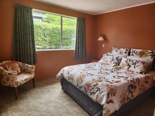 a bedroom with a bed and a chair and a window at The Willow - Hanmer Springs Holiday Home in Hanmer Springs