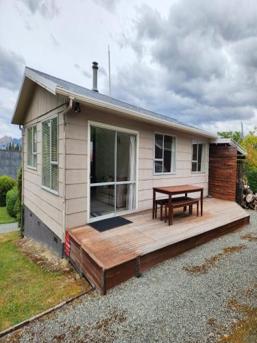 a house with a wooden deck with a table at The Willow - Hanmer Springs Holiday Home in Hanmer Springs