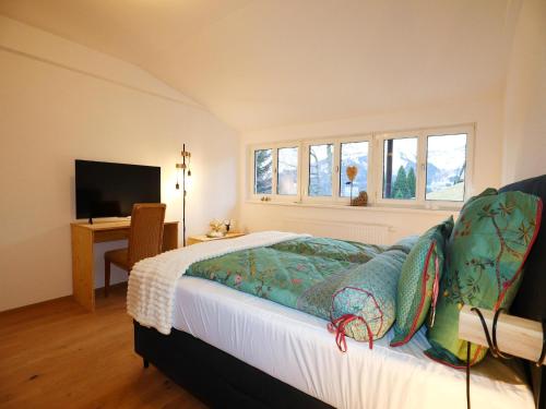 a bedroom with a bed with a television and windows at Holiday apartment in Bregenzerwald in Sibratsgfäll