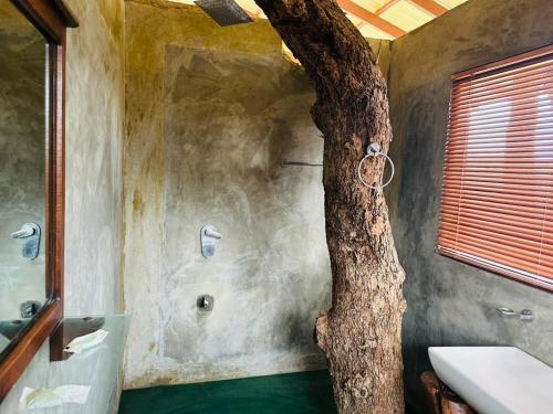 a bathroom with a tree in the middle of a bathroom with a tree trunk at Green Heaven Sigiriya in Sigiriya
