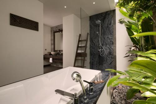 a bathroom with a tub, sink and mirror at Akana Boutique Hotel in Sanur