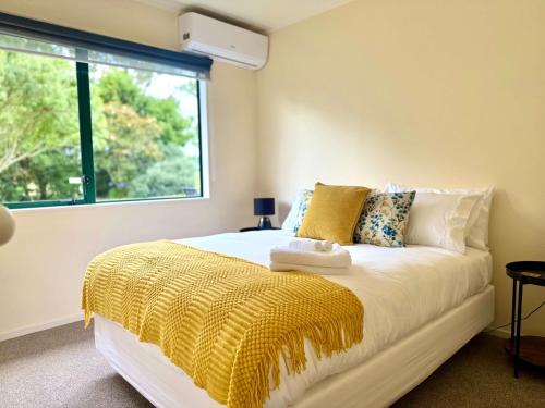 a bedroom with a bed with a yellow blanket on it at Peaceful Country Escape in Gordonton - Green Meadows Cottage in Taupiri