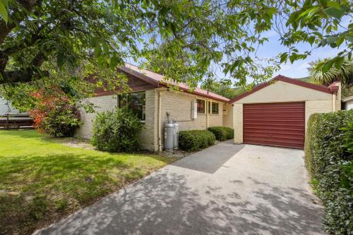 a house with a red garage at Rees on Reid - Arrowtown Holiday Home in Arrowtown