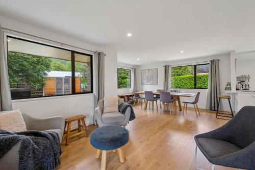 a living room with chairs and a table and windows at Rees on Reid - Arrowtown Holiday Home in Arrowtown