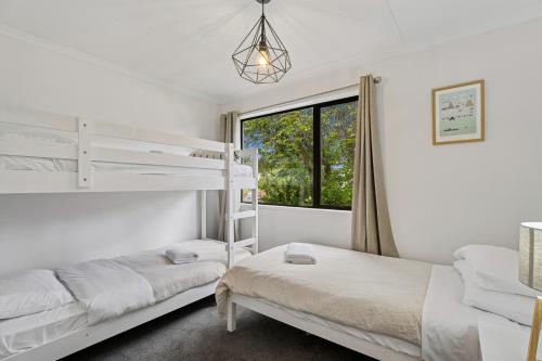 a bedroom with two bunk beds and a window at Rees on Reid - Arrowtown Holiday Home in Arrowtown