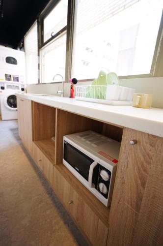 a kitchen with a counter with a microwave in it at Cavemen Hostel Taipei Station Youth Branch in Taipei
