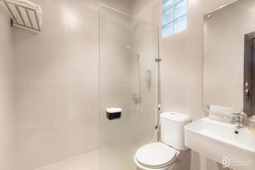 a white bathroom with a toilet and a shower at Hotel Grand Panorama Lembang in Lembang